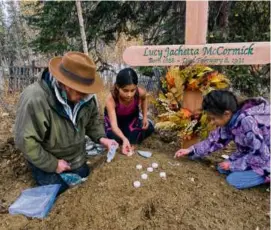  ?? WALLY CARLO VIA ASSOCIATED PRESS ?? Family members placed candles and stones at the grave of Lucy Pitka McCormick, one of the Lost Alaskans, during a reburial ceremony in Rampart, Alaska, in September.