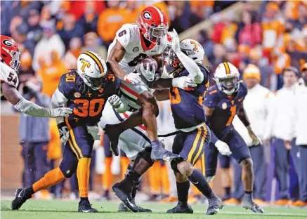  ?? AP PHOTO/WADE PAYNE ?? Georgia running back Kenny McIntosh leaps as he’s hit by Tennessee linebacker­s Roman Harrison (30) and Jeremy Banks during the second half Saturday in Knoxville.