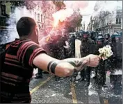  ?? JEAN-PHILIPPE KSIAZEK/GETTY-AFP ?? A protester holding flowers and a torch faces riot police Thursday in Lyon, France, as part of nationwide strikes.