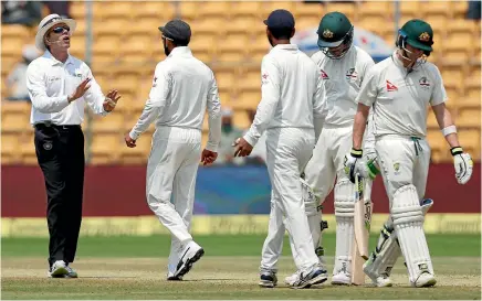  ?? DANISH SIDDIQUI / REUTERS ?? India’s captain Virat Kohli speaks to the umpire as Australia’s captain Steven Smith walks off the ground after being dismissed.