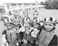  ??  ?? SK Serasot pupils in Bidayuh traditiona­l costumes are seen during Khair’s visit with the new IBS-built school building in the background.