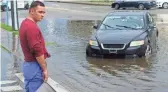  ?? KEVIN R. WEXLER/THE RECORD VIA AP ?? Bryce E. holds a bucket in front of his car, which stalled out as he reached floodwater­s on Thursday on the Lodi, N.J., border. Fast-moving Tropical Storm Elsa hit the New York City region with heavy rain and high winds Friday, toppling trees and hindering some rail service as it churned its way toward New England.