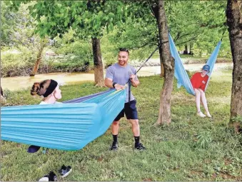  ?? Joyce Young ?? Aaron King is set to swing Holly Moore before jumping back into his own hammock as Halle Moore looks on. The three have spent several recent afternoons visiting as they relaxed in hammocks at Palmer Memorial Park at the Calhoun City Recreation Center. Check out today’s Gordon Life section for an article about local park offerings and more photos.