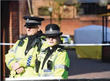  ?? CHRIS J RATCLIFFE/AFP ?? Police stand guard at a cordon at the scene at The Maltings shopping centre in Salisbury, southern England, yesterday where a man and a woman were found critically ill on a bench.