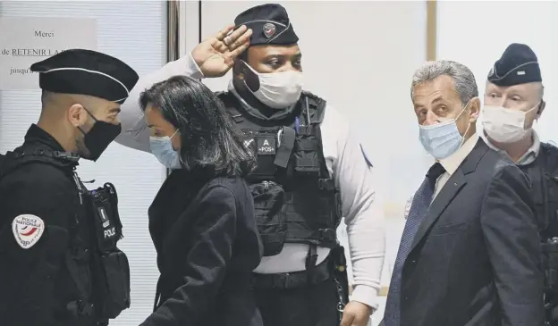  ??  ?? 0 An officer salutes as former French president Nicolas Sarkozy arrives at the Paris court house to hear the final verdict in his corruption trial