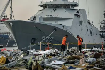  ?? Associated Press ?? ■ Members of National Search and Rescue Agency inspect debris retrieved from the waters where Lion Air flight JT 610 is believed to have crashed Wednesday at Tanjung Priok Port in Jakarta, Indonesia. A massive search effort has identified the possible seabed location of the crashed Lion Air jet, Indonesia's military chief said Wednesday, as experts carried out the grim task of identifyin­g dozens of body parts recovered from a 15-nautical-mile-wide search area.