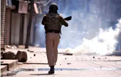  ??  ?? File photo shows an Indian policeman chasing after protesters amid tear gas smoke during a protest after Jumat-ul-Vida or the last Friday prayers of the holy fasting month of Ramadan, in Srinagar. — Reuters photo