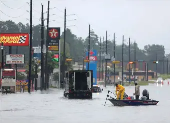  ??  ?? Rescuers in a boat move down a street covered in floodwater­s from Hurricane Harvey in Texas