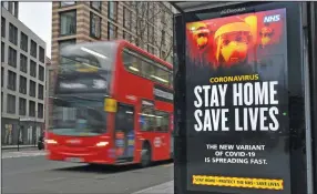  ?? (AP/PA/Dominic Lipinski) ?? A London Transport double-decker bus on Friday passes a sign advising pandemic restrictio­ns as England begins its third national lockdown to curb the spread of coronaviru­s.