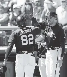  ?? ASSOCIATED PRESS FILE PHOTO ?? The Atlanta Braves’ Ronald Acuna Jr. gets a high-five from Freddie Freeman, right, after hitting a home run in the third inning of a spring baseball exhibition game in Kissimmee, Fla.