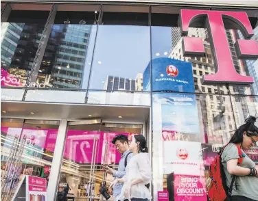  ?? Brittainy Newman / New York Times 2019 ?? People pass by the TMobile store in New York in June. A judge ruled in favor of the merger with Sprint.