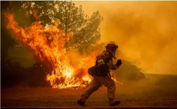  ?? PhoTo/NoAh Berger ?? In this July 31 file photo, a firefighte­r runs while trying to save a home as a wildfire tears through Lakeport, Calif. AP