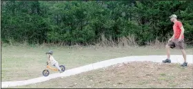  ??  ?? Jack Crouse, 3, sails down a slope on the pump track near Cooper Elementary School in Bella Vista while his father John Crouse supervises.