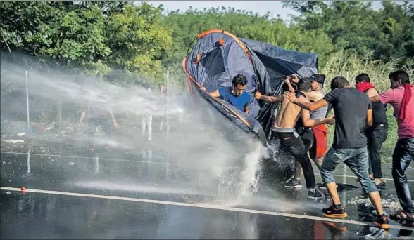  ?? TAMAS SOKI / AP ?? La policía húngara usó un cañón de agua contra los migrantes que intentaban cruzar a Hungría desde Horgos, en Serbia