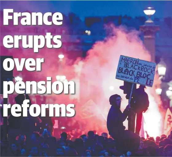  ?? Pictures: AFP ?? A protester on a traffic light in Paris holds a placard while surrounded by hundreds of other angry demonstrat­ors.