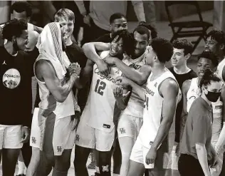  ?? Karen Warren / Staff photograph­er ?? UH players hug Tramon Mark after the freshman drained a near half-court 3-pointer to beat Memphis on Sunday in the regular-season finale at the Fertitta Center in Houston.