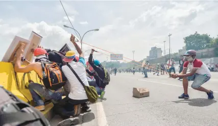  ?? — AFP ?? Opposition demonstrat­ors use a slingshot in clashes with the riot police during a protest against Venezuelan President Nicolas Maduro in Caracas.