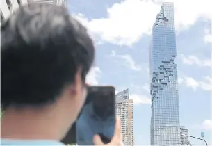  ?? JIRAPORN KUHAKAN ?? A man taking a shot of the MahaNakhon Building, developed by Pace Developmen­t Co.