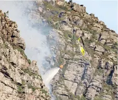  ?? IAN MERRINGTON Twitter ?? THE Huey from Working on Fire puts a damper on the Table Mountain ravine fire on Saturday afternoon. |