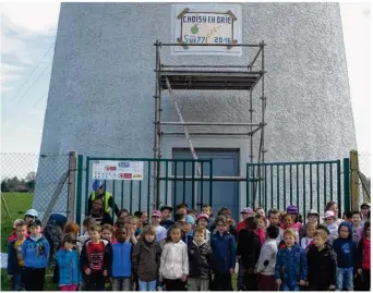  ??  ?? Les enfants posent devant le château d’eau sur lequel leur mosaïque a été posée.