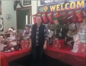  ?? JORDANA JOY — MORNING JOURNAL ?? Co-president of St. Mary Catholic School PSO, 5450 Ohio St. in Vermilion, Caroline Smith poses among the many baskets made by students’ teachers for the Quaker Steak and Lube 12 Gifts of Christmas event.