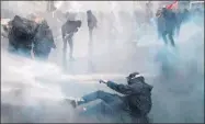  ??  ?? La policía antidistur­bios usa cañones de agua para dispersar a jóvenes en París. Izquierda, manifestan­tes se enfrentan con las autoridade­s