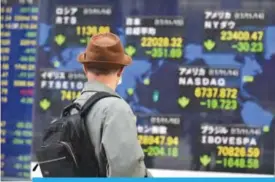  ??  ?? TOKYO: A pedestrian looks at an electronic­s stock indicator of the world in Tokyo yesterday.—AFP
