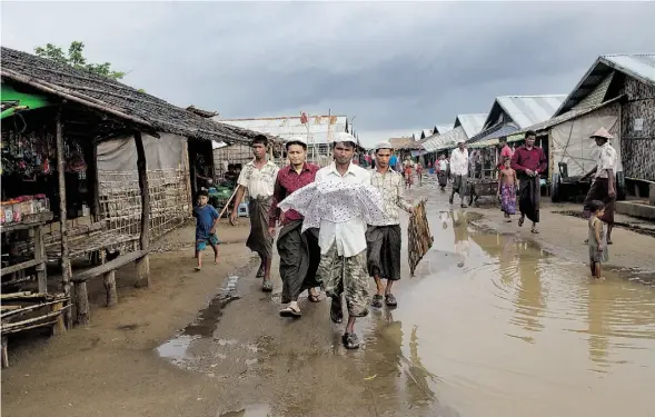  ?? GEMUNU AMARASINGH­E/THE ASSOCIATED PRESS ?? Yusuf, 31, carries the corpse of his niece through the flooded streets of a squalid camp for Rohingya Muslim refugees in Rakhine state, Myanmar.