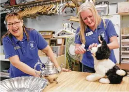  ??  ?? Williams, left, laughs with Allison Rankin as they check out a robotic dog at St. Christophe­r’s Resale Shop.