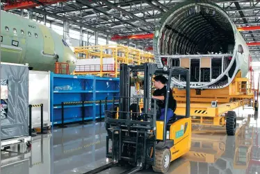  ?? TIAN HE / FOR CHINA DAILY ?? An employee drives a forklift at an assembly line for Airbus A320 aircraft in Tianjin.