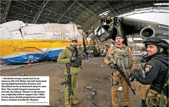  ?? Vadim Ghirda/Associated Press ?? Ukrainian troops stand next to an Antonov AN-225 ‘Mriya’ aircraft destroyed during fighting between Russian and Ukrainian forces at Hostomel airport, near Kiev. The world’s largest commercial aircraft, the ‘Mriya’ (‘dream’ in Ukrainian) was originally built to support the 1980s Soviet space shuttle programme and had been a symbol of pride for Ukraine.