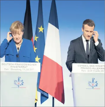  ??  ?? Angela Merkel, Germany’s chancellor, left, and Emmanuel Macron, France’s president, adjust their earpieces during a news conference following a Franco-German joint cabinet meeting at the Elysee Palace in Paris yesterday.