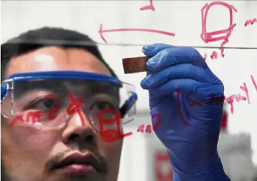  ?? — AFP ?? Cracking the problem: Yanagisawa looking at a piece of repaired broken resin glass after pressing the pieces back together at the university’s lab in Tokyo.