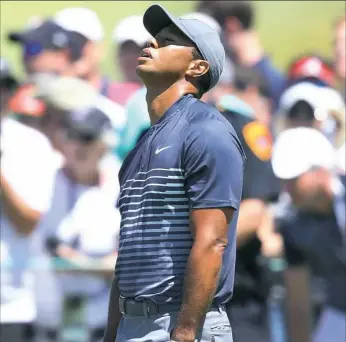  ?? Warren Little/Getty Images ?? Trouble started early for Tiger Woods as he reacts to his second shot on the opening hole Thursday.