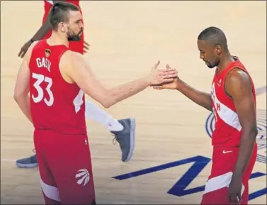  ??  ?? Los jugadores Marc Gasol y Serge Ibaka se saludan en mitad de un partido de los Raptors.