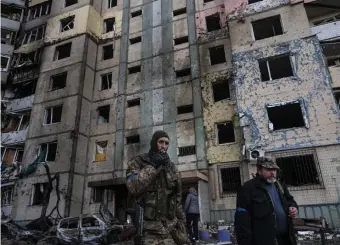  ?? Ap pHotos ?? ANOTHER BUILDING DESTROYED: A soldier smokes a cigarette while walking next to a destroyed building after a bombing in Satoya neighborho­od in Kyiv, Ukraine, Sunday.