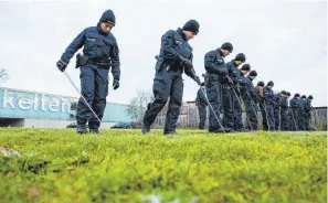  ?? FOTOS: LENNART PREISS/DPA ?? Einsatzkrä­fte der Bereitscha­ftspolizei suchen nach dem Diebstahl des Kelten-Goldschatz­es die Umgebung des Museums in Manching mit Metalldete­ktoren nach möglichen Spuren ab.