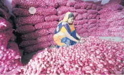  ?? AJIT SOLANKI/AP ?? An Indian trader checks onions at a market in Ahmadabad. Prices have soared recently.
