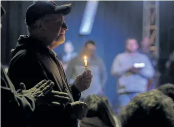  ?? RYAN HERMENS/THE PADUCAH SUN VIA AP ?? Stan Collins of Benton, second from left, holds a candle during a vigil at Impact Church in Benton, Ky., on Tuesday. The vigil was held for victims of the Marshall County High School shooting.