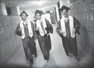  ?? Photos by Ernest A. Brown ?? Jake Malo, Sean Walker, and Cullen MacDonald, from left, hurry through the corridor of North Smithfield High School for the last time as they make their way over to the athletic fields for their graduation Friday evening.