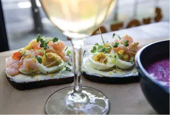  ?? Tribune News Service ?? ■ A window seat at La Dive restaurant shows off the cocktail shrimp open-faced sandwhiche­s that are popular along with the Chlodnik at right — chilled beet poup with kefir.