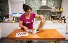  ??  ?? Jayne Zhou empties the contents of a bag containing a Hello Fresh cajun fish tacos meal kit, before preparing it at her home in Vancouver, B. C.