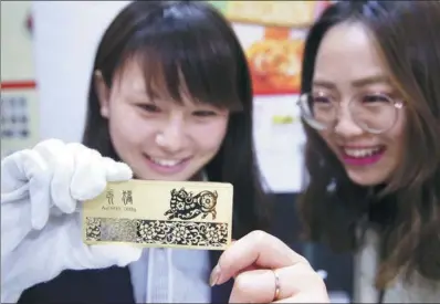  ?? CHEN XIAOGEN / FOR CHINA DAILY ?? Employees introduce a gold bar made with 500 grams of 99.99 percent pure gold to celebrate the coming Year of the Pig at the Beijing Internatio­nal Coin Exposition 2018 on Nov 10.