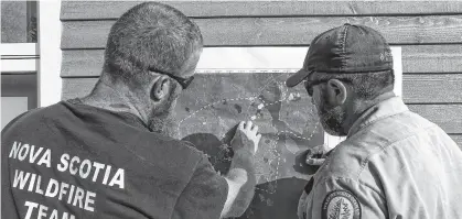  ?? COMMUNICAT­IONS NOVA SCOTIA ?? Cory Isenor, left, Operations Section Chief from Kentville, and Ken Cox, Air Operations Chief from Bible Hill, look at the map of the Barrington Lake fire during a Friday morning briefing.