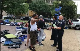  ?? (AP/Dylan Lovan) ?? A protester speaks Sunday with Louisville, Ky., police officers who were handing out flyers on an overnight camping ban.