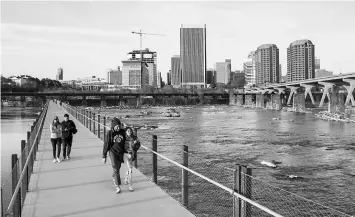  ??  ?? Pedestrian­s cross the James River on the T. Tyler Potterfiel­d Memorial Bridge with the skyline of Richmond, Virginia, in the background.