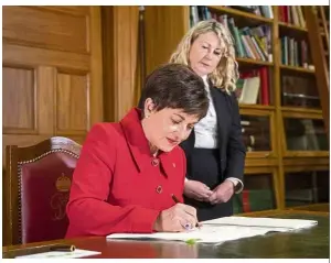  ?? — AP ?? Making it official: New Zealand governor general Patsy Reddy signing into effect sweeping gun laws outlawing military-style weapons at Government House in Wellington.