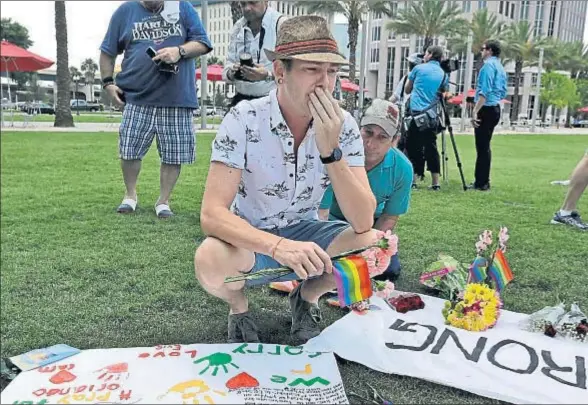  ?? CHRIS OMEARA / AP ?? Johnathan Dalton recordando a sus amigos muertos en el club Pulse con unos claveles y la bandera del arco iris, ayer en Orlando