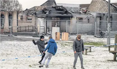  ?? Picture: Wullie Marr. ?? Youngsters play in front of the fire-ravaged Cairneyhil­l Primary School.