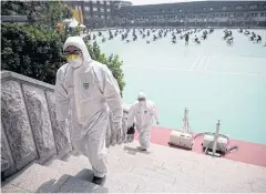  ?? REUTERS ?? People in personal protective equipment walk up a flight of stairs as South Korean job seekers attend an exam.